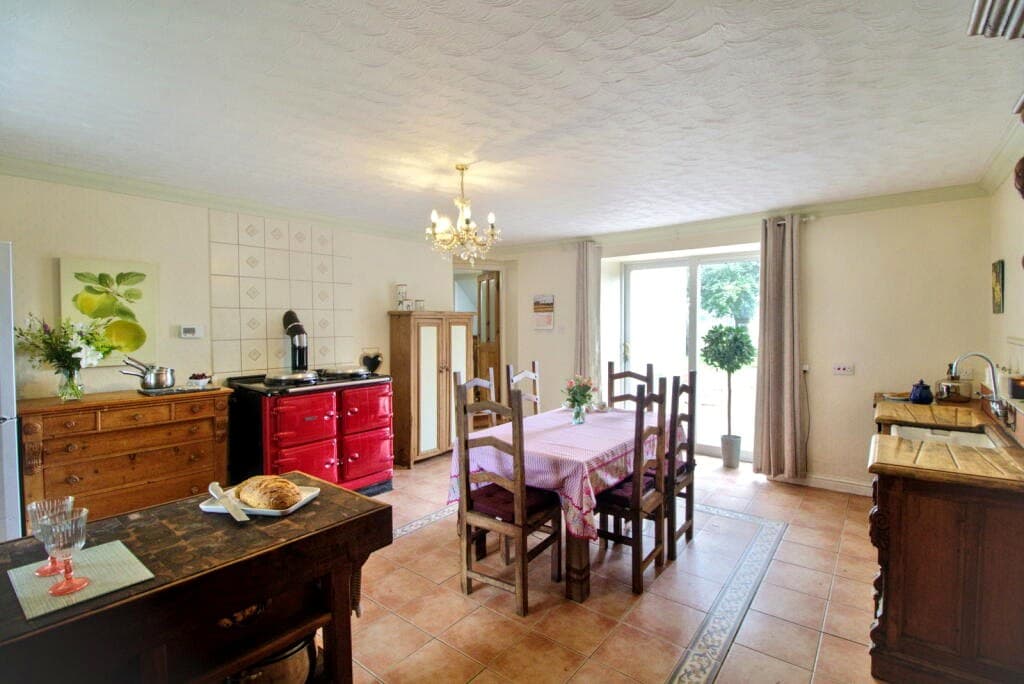 Country kitchen with red Rayburn-Aga, dining area and patio doors